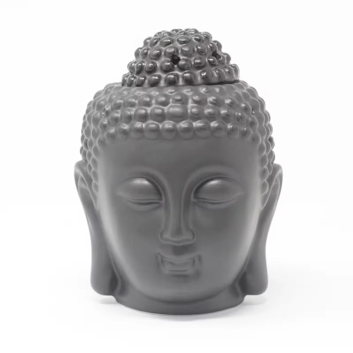 Dark brown Buddha head oil burner figurine displayed on a ceramic plate.