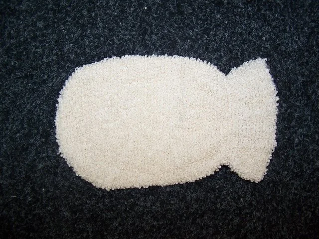 Bamboo cleaning mitt wrapped in soft, natural bamboo fibers, displayed on a light wooden surface.