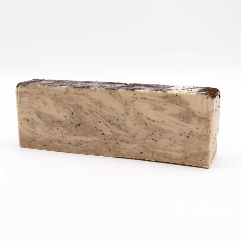 Loaf of coconut soap with olive oil aroma, square shaped bar on rustic wooden background.