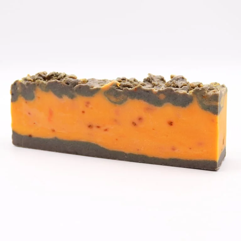 Olive oil soap loaf scented with cinnamon and orange, golden‑amber foam texture.