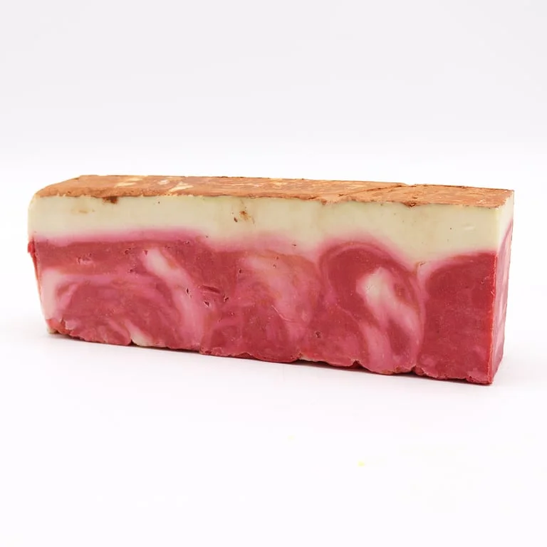 Red clay soap loaf made with olive oil, displayed on natural wooden surface.