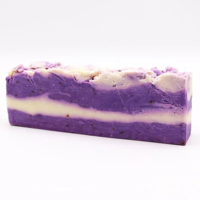 Lavender olive oil soap loaf on cutting board, sliced into blocks, with a light lavender hue and smooth texture.