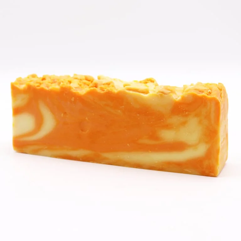 Loaf of orange soap with olive oil finish, creamy texture and bright citrus design.