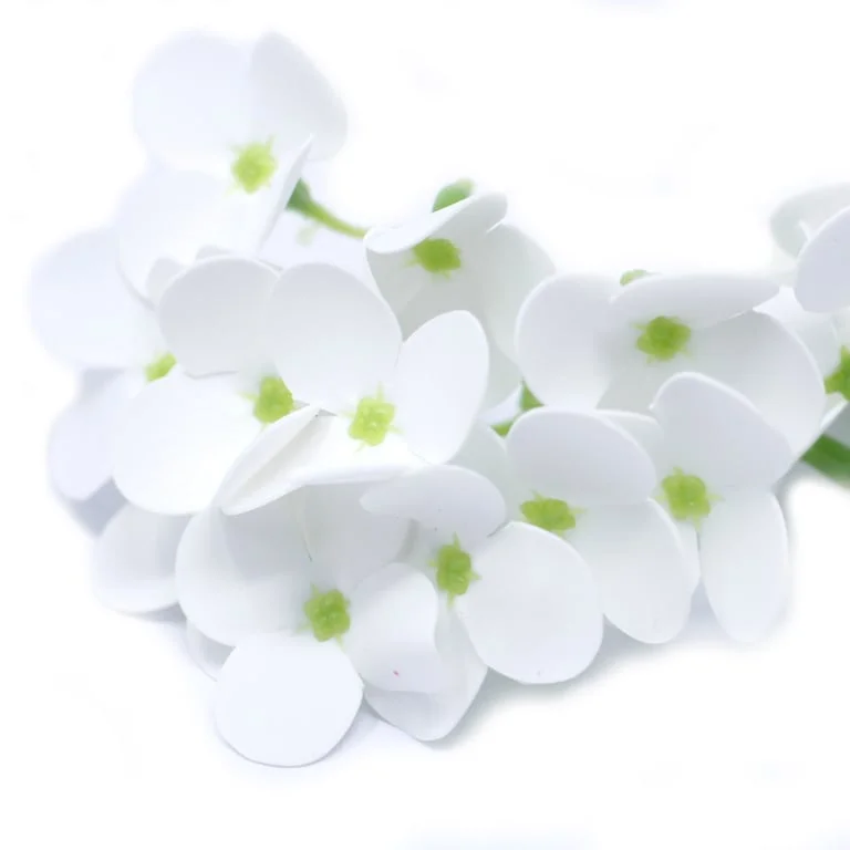 White craft soap flower shaped like a hyacinth bean, displayed in a gentle floral setting