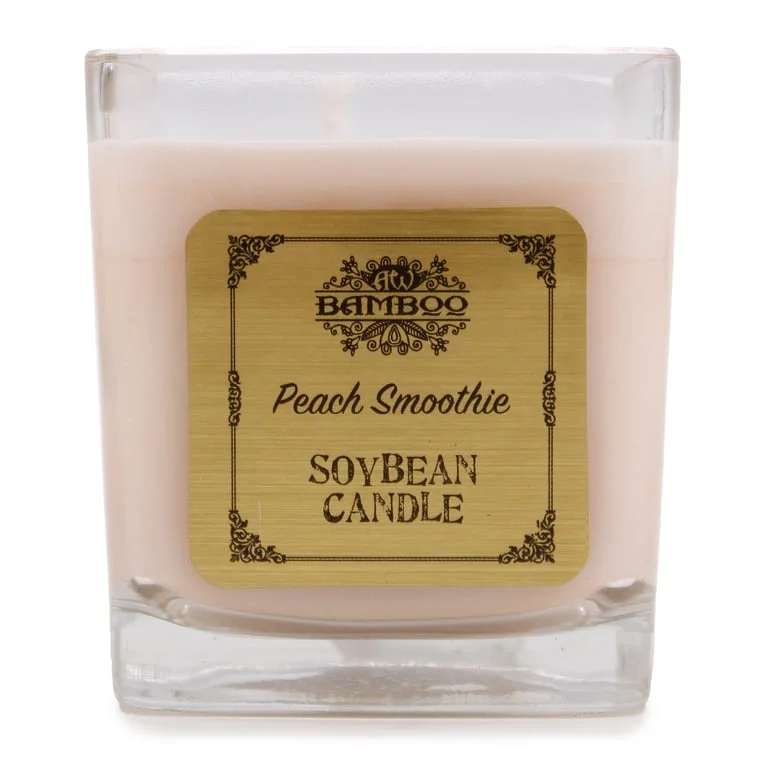 Peach soy candle in a clear glass jar, softly glowing.