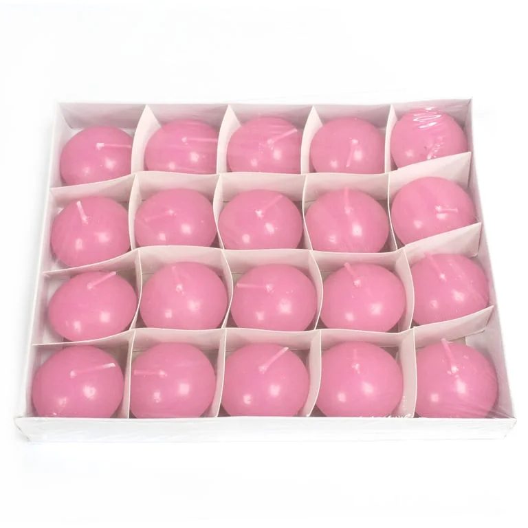 Small pink floating candle glowing in water.