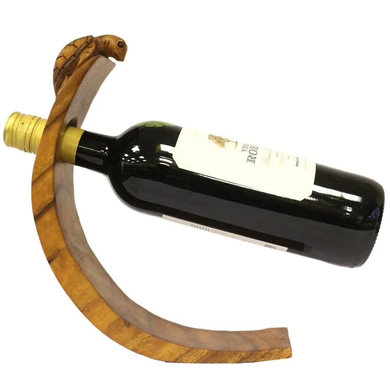 Turtle-shaped wine bottle holder balanced on a base, displayed in a photo.