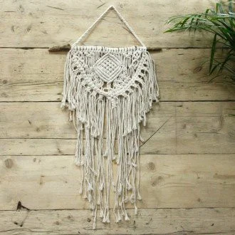 Macrame wall hanging hanging on a wall.