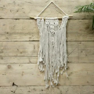 Colorful macrame wall hanging draped across a wall with intricate knotting.