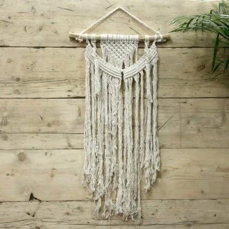 Macrame wall hanging with woven natural motifs, hanging from a wooden dowel.