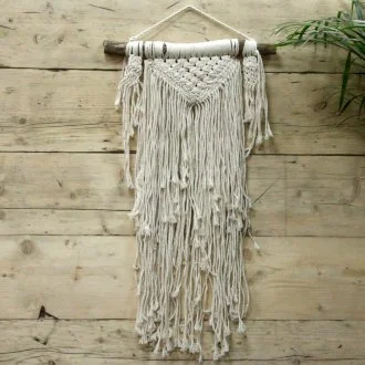macrame wall hanging with natural fibers, intricate knotted design suspended against a neutral backdrop.