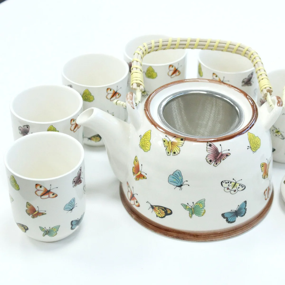 Herbal teapot set with butterfly designs, including a matching teapot and cup.