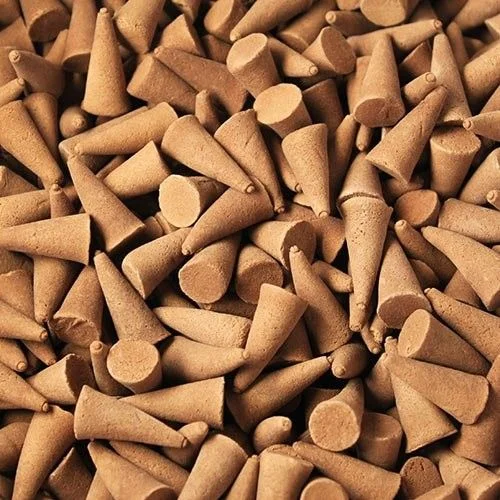 Stack of bulk incense cones in orange and cinnamon scents, shiny cones bundled together.