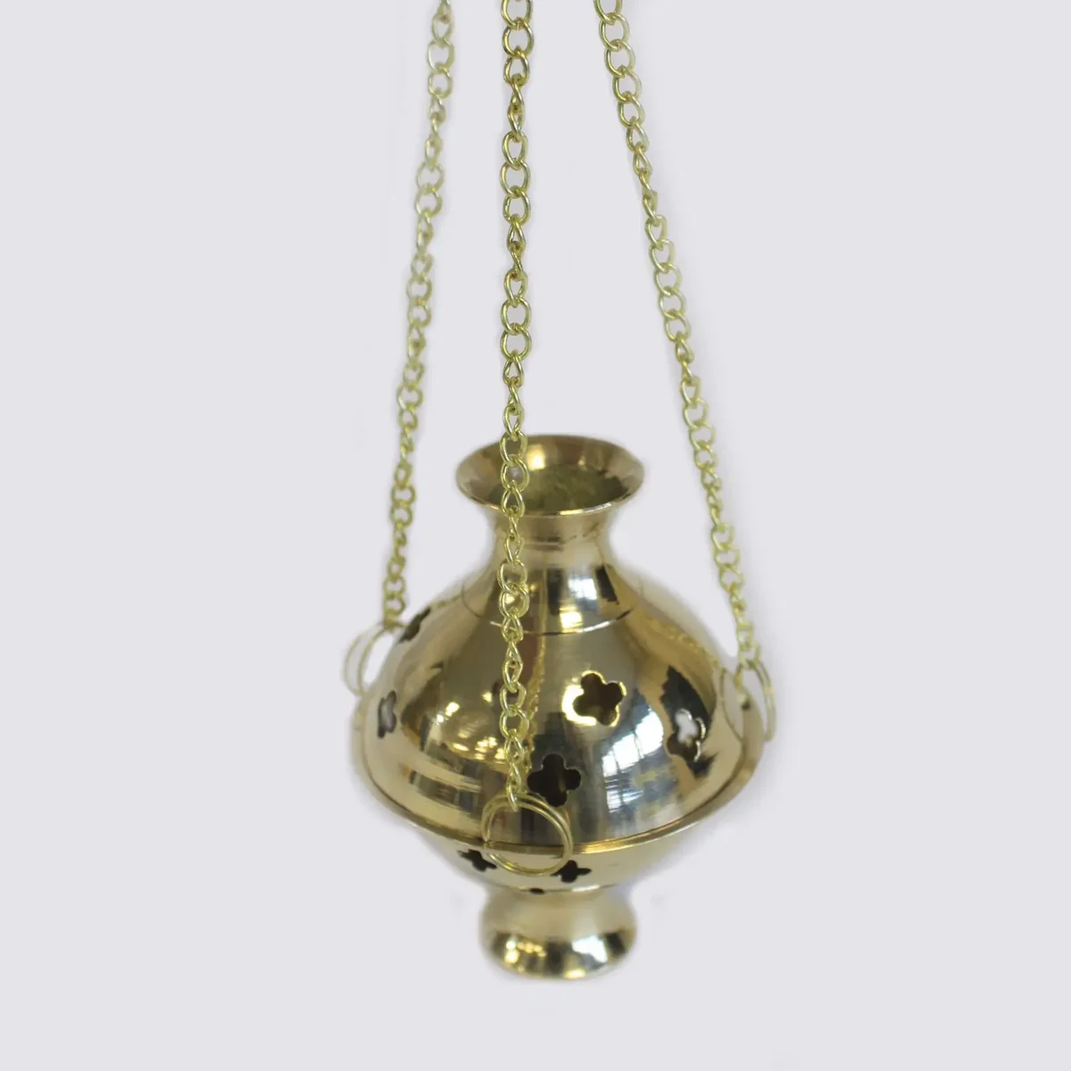 Hanging incense holder in polished brass, suspended from a hook, featuring a conical burner for incense sticks.