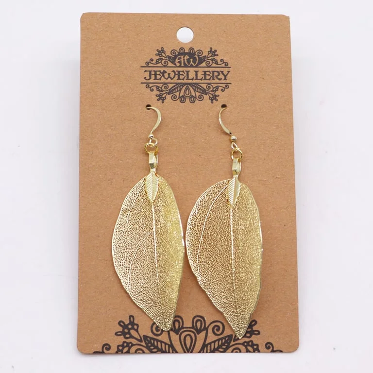 Gold leaf design earrings displayed on a hand against a muted backdrop.
