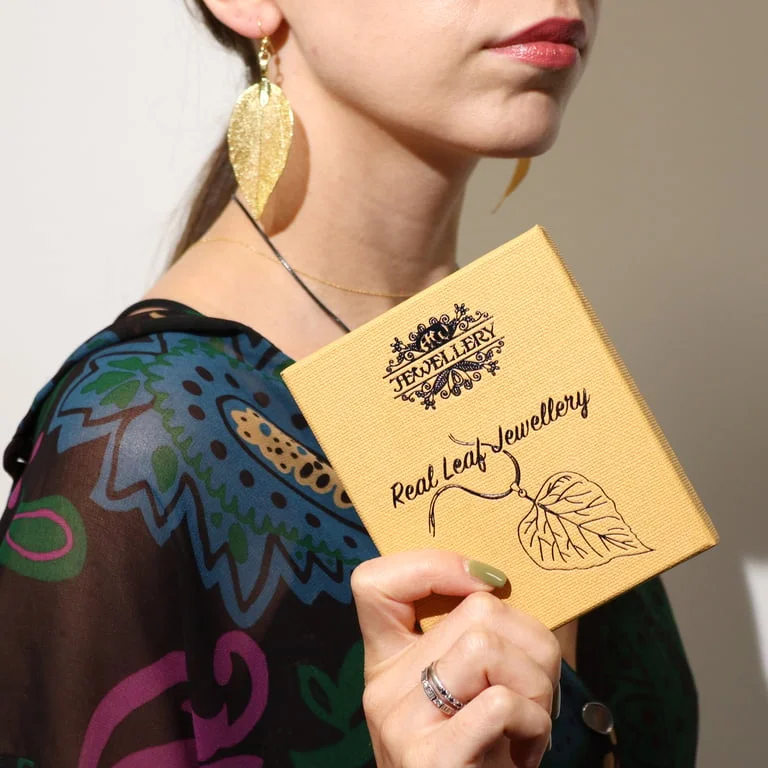 Gold bravery leaf earrings featuring a delicate leaf design, shown hanging from a slender gold hook.