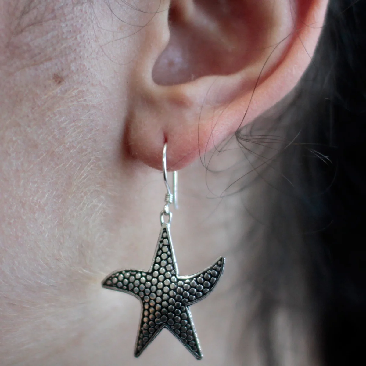 Silver starfish-shaped star fish earrings displayed in polished arrangement