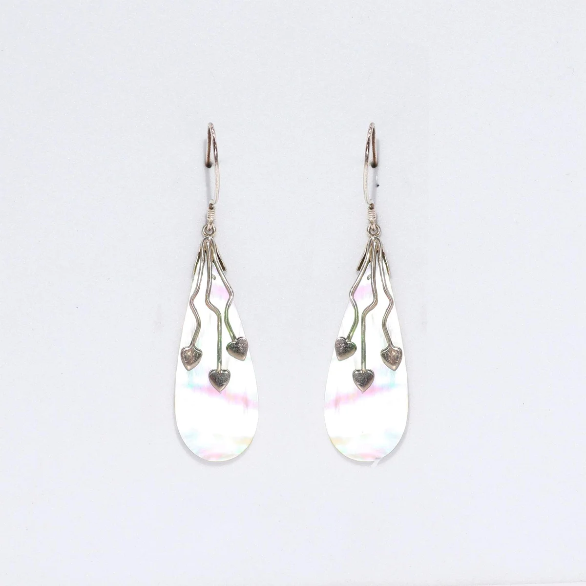 Three heart‑shaped shell silver earrings hanging from silver hooks.