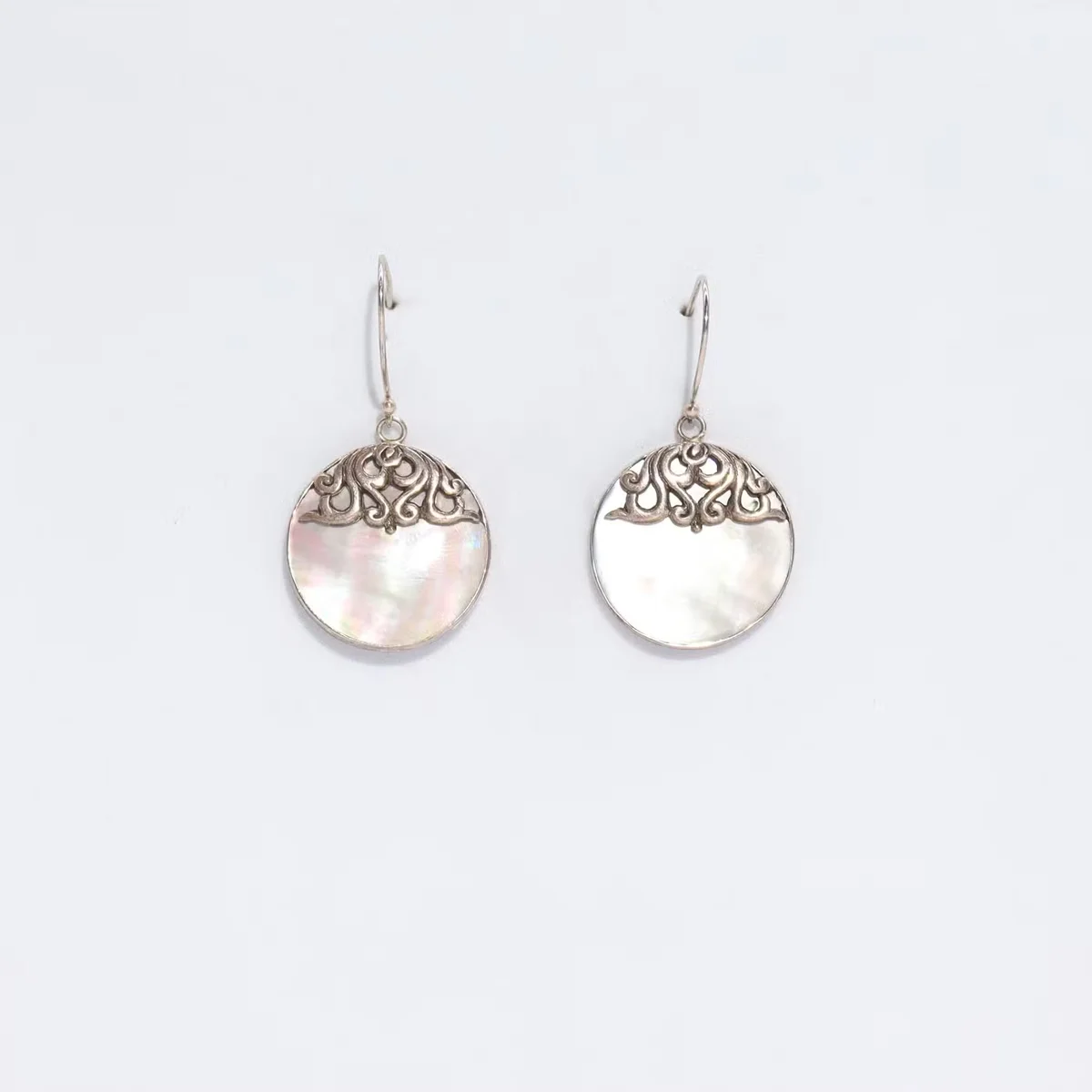 Shell and silver classic disc earrings shown together.