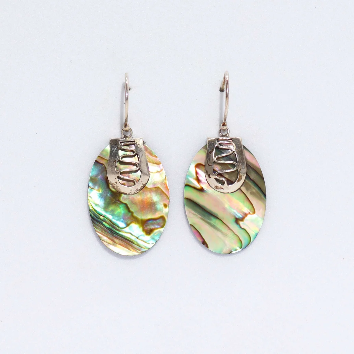 Abalone shell earrings with silver accents shown on a plain background
