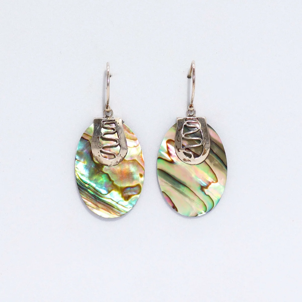 Abalone shell silver earrings hanging from silver cords, showcasing natural shell pattern against a subtle silver finish.
