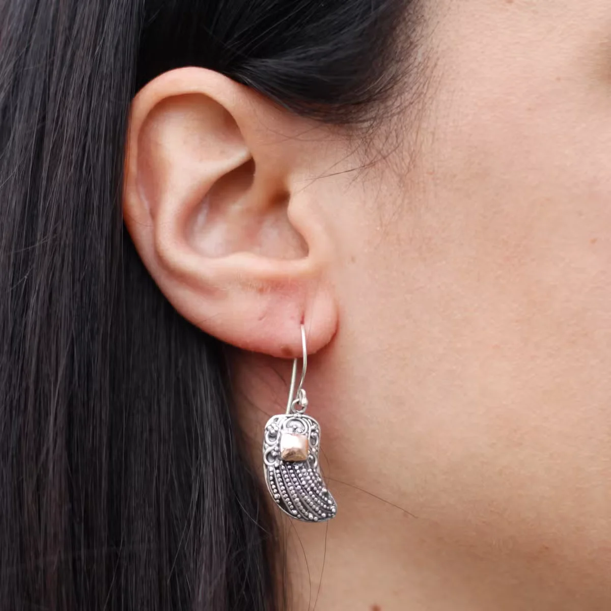 Gold and silver wing shaped earrings featuring angel wing design in a close‑up shot.