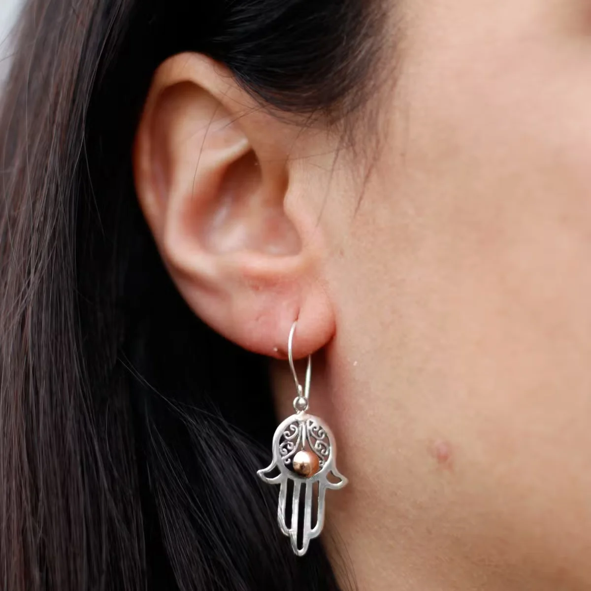 Silver and gold hamsa jewellery earring, small pendant with hand motif, displayed on plain background