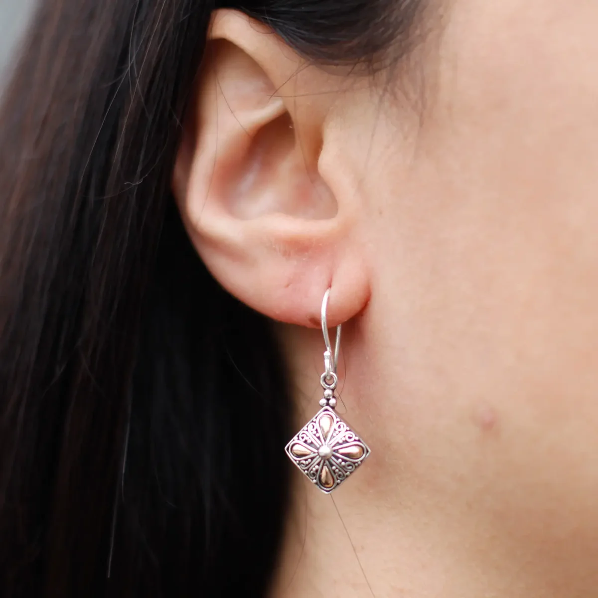 Silver and gold square drop earrings with a sleek, modern design hanging against a white background