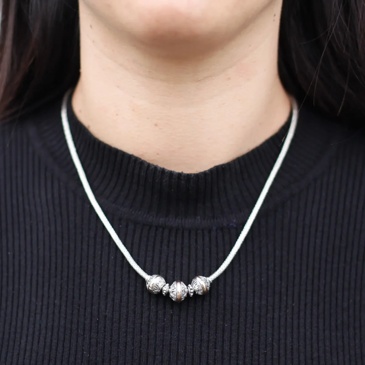 Silver and gold necklace with a triangular pendant.