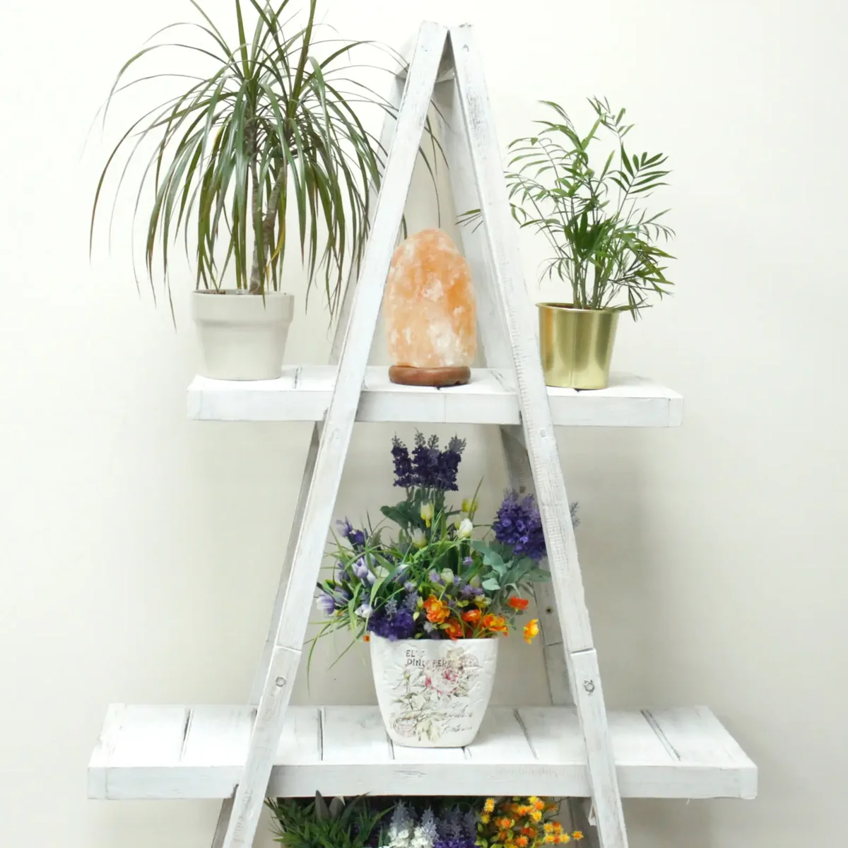 Whitewashed folding wooden A‑frame shelf in partially unfolded position, showing its geometric frame and light finish.