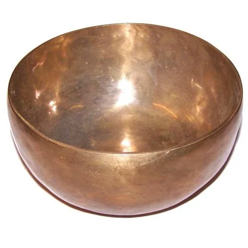 Extra large handmade singing bowl on a wooden base, round shape highlighted by soft natural light.