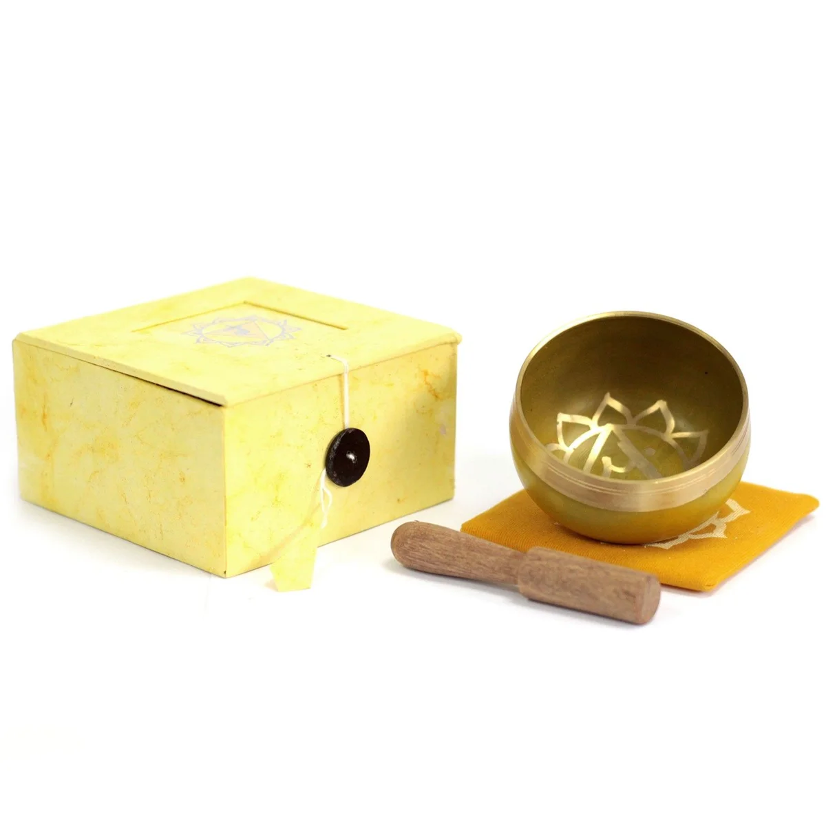 Solar plexus singing bowl sits on a soft stone slab, its polished metal rim catching soft light.