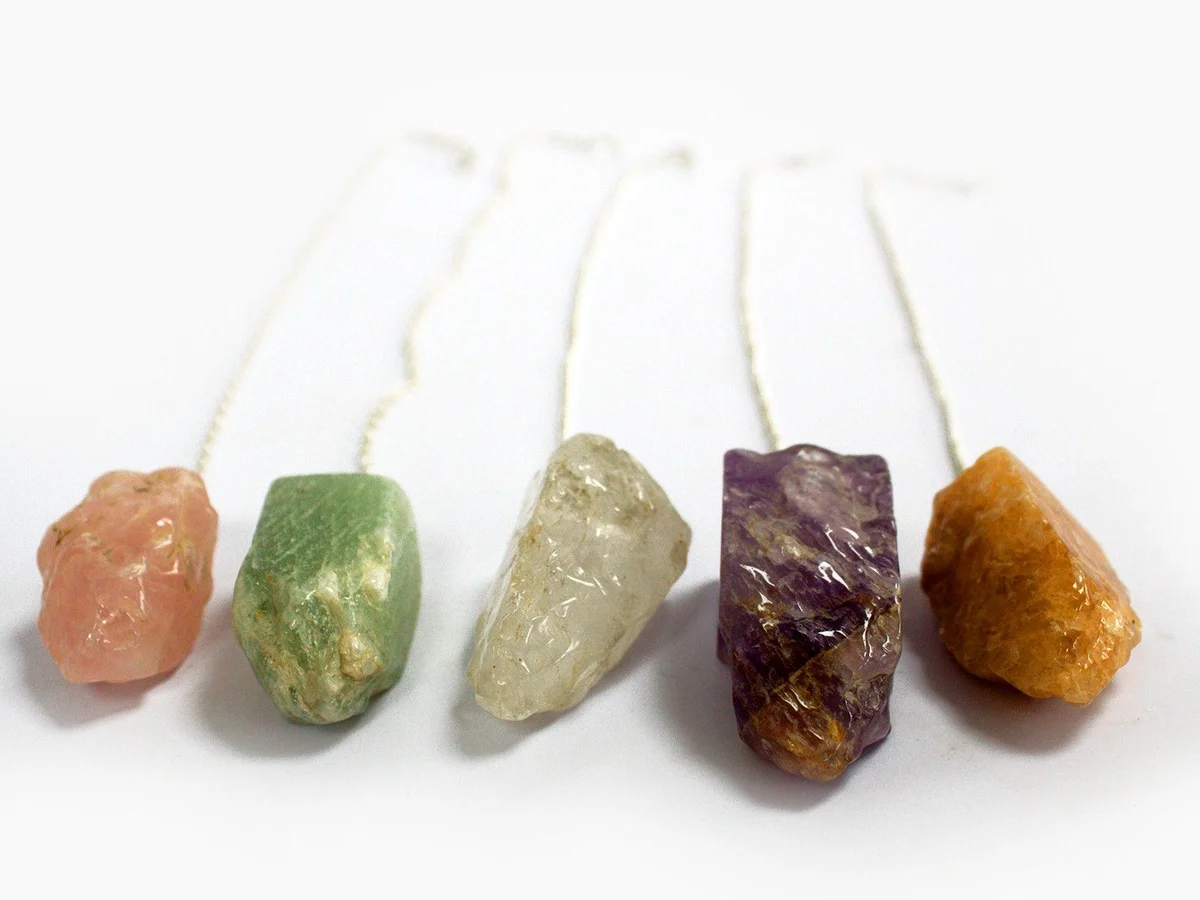 Assorted natural stone pendulums hanging from bright cords, each a natural stone pendulum.