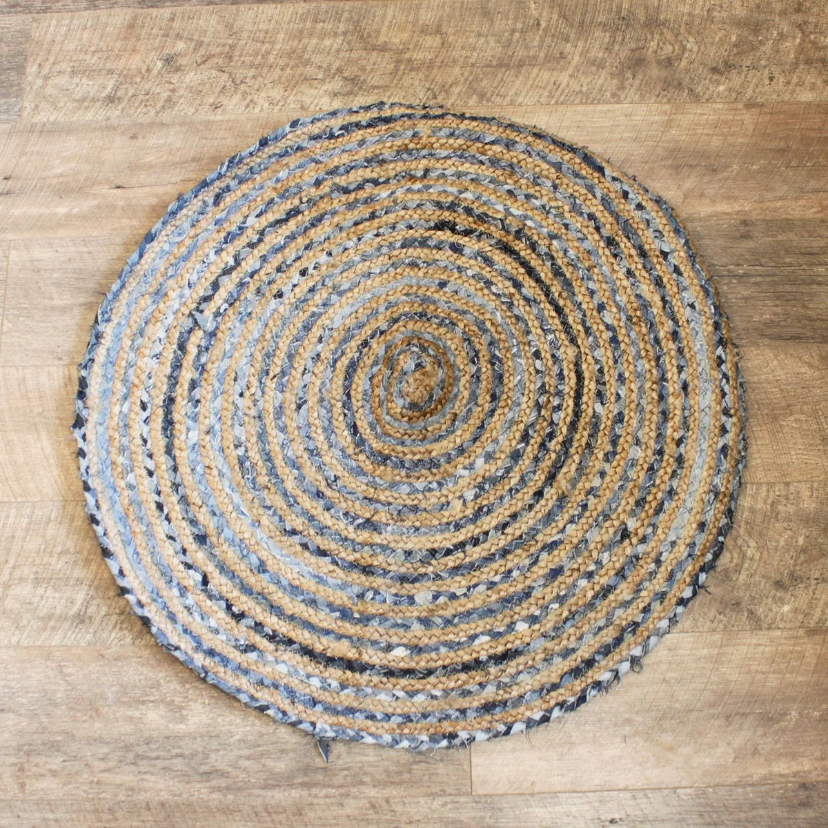 Round jute rug in soft texture, featuring a denim trim around the circular edge.