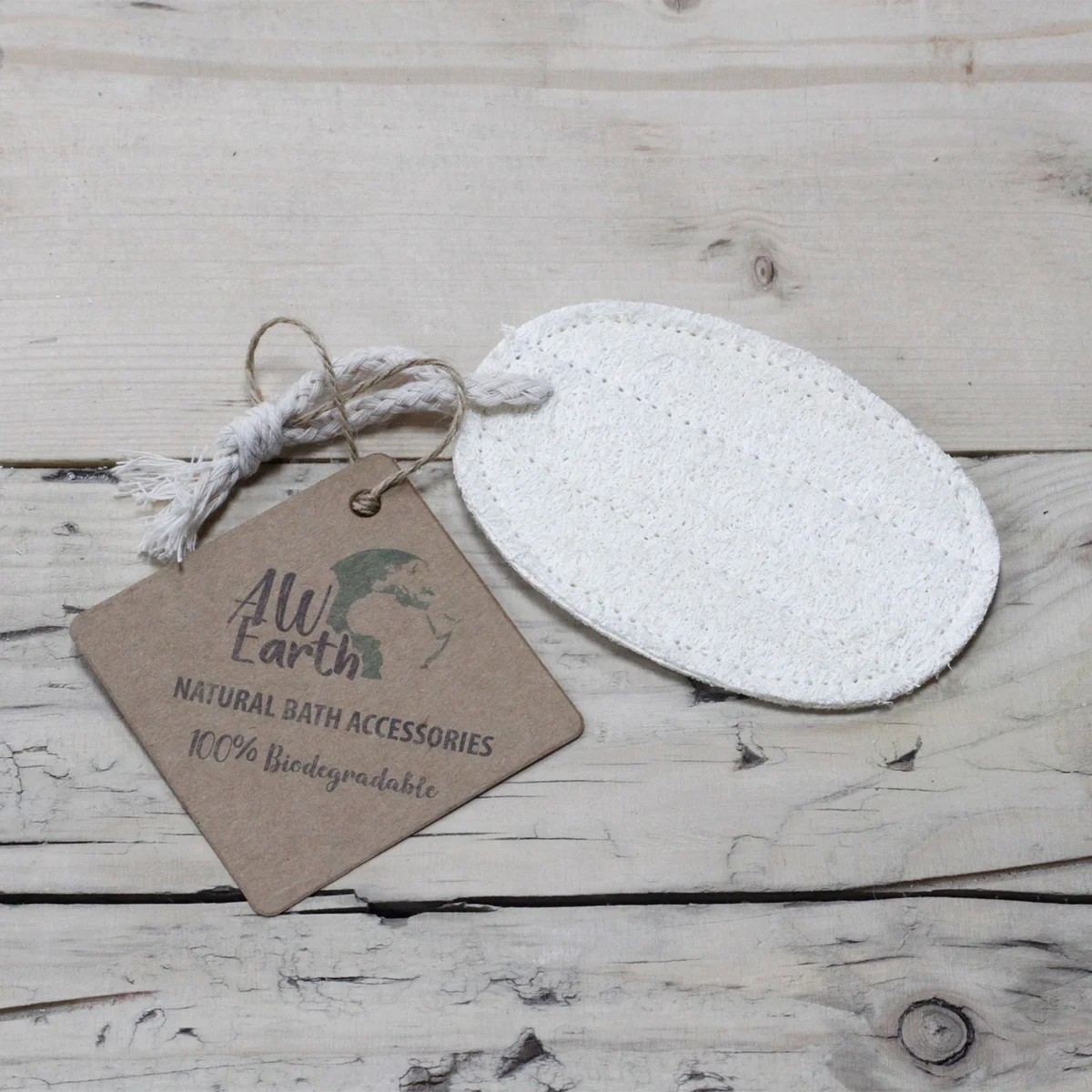 Oval loofah scrub in natural beige, placed on a bathroom counter with towels.