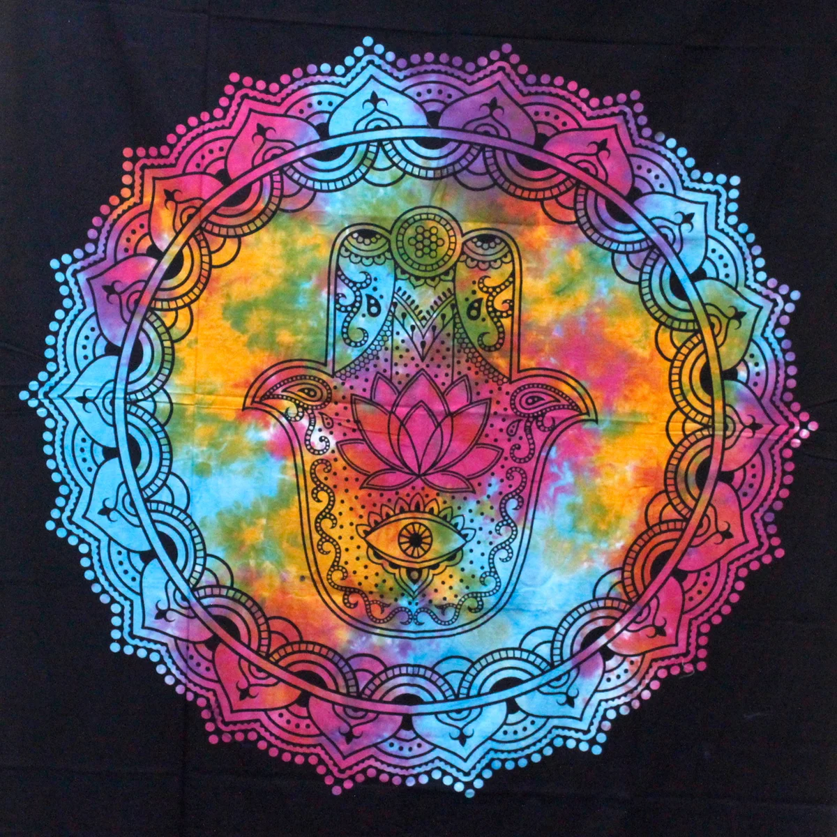 Black hamsa wall hanging beside double cotton bedspread on bed
