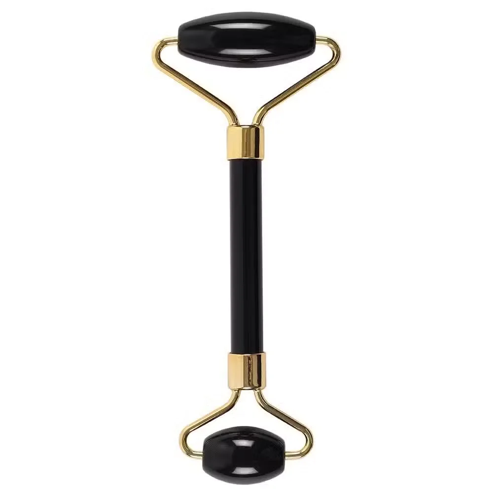 Black obsidian gemstone facial massage roller with smooth polished stones on a wooden surface