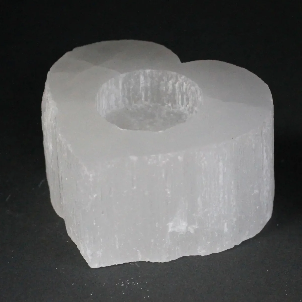 Selenite heart candle holder, clear crystal heart shape glowing with a small candle.
