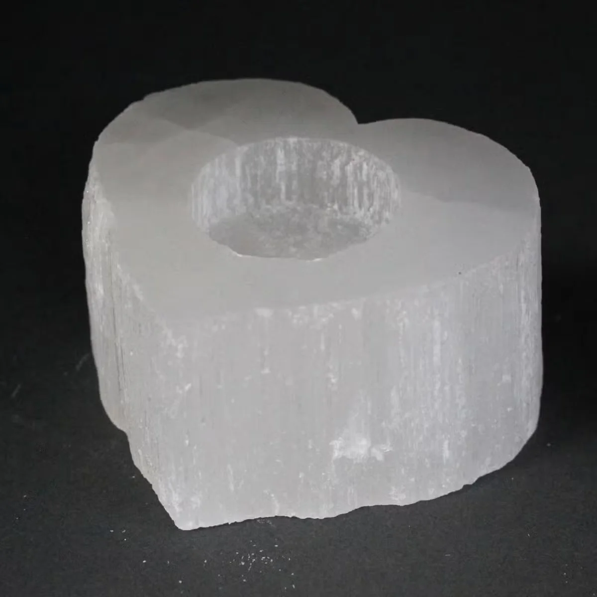 Selenite crystal heart candle holder, translucent crystal with heart shape, elegant glass design, lit candle.