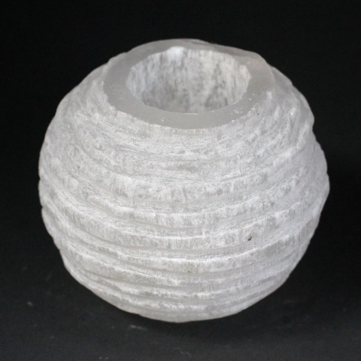 8 cm selenite candle holder shaped like a snowball, glistening white crystal on a flat surface