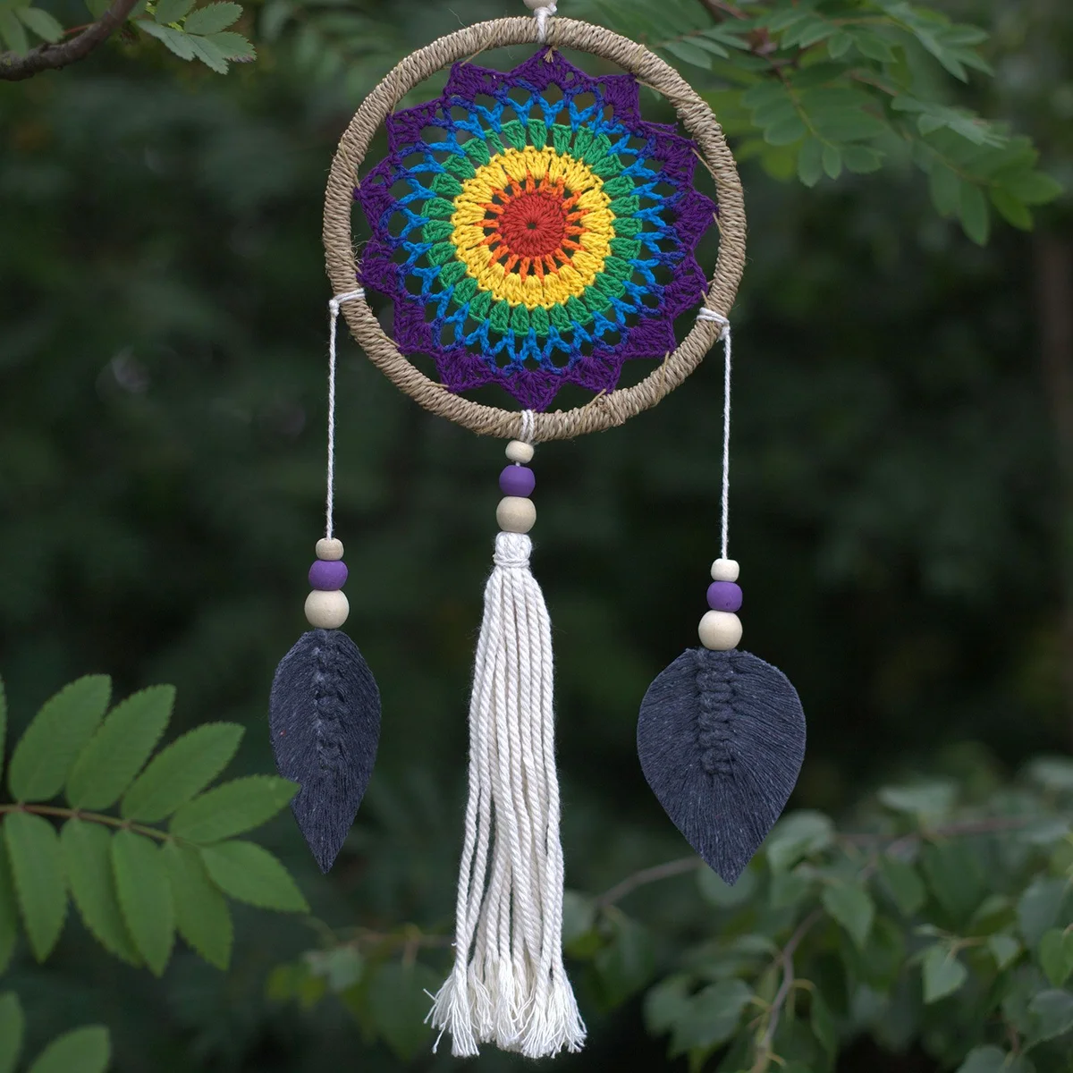 Medium dream catcher featuring a rainbow design inspired by elemental spirits hanging on a wall background