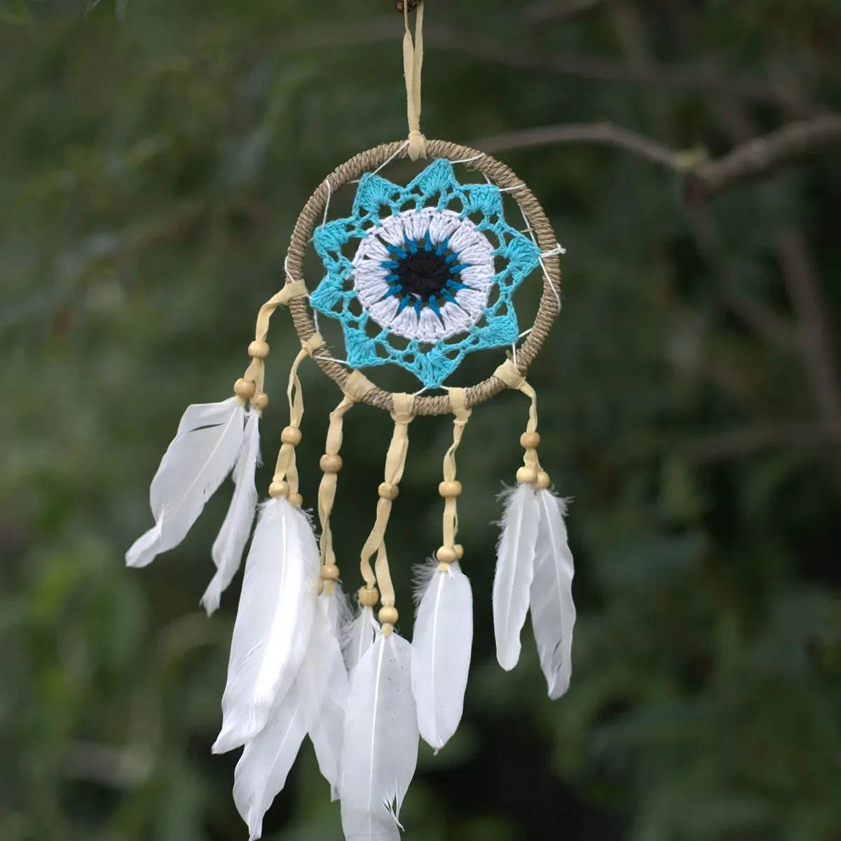 Pastel blue macramé dream catcher with intricate web design and hanging tassels, 12cm diameter