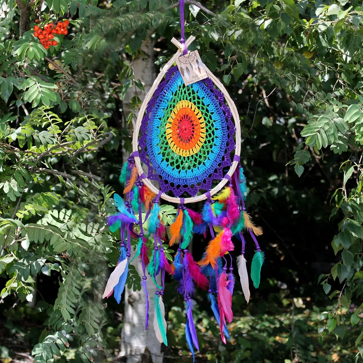 Large multi teardrop Bali dream catcher with intricate web design and hanging feathers against white background
