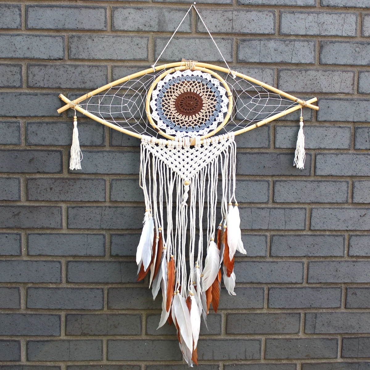 Large macrame dream catcher with white, grey, and brown threads featuring an evil eye wall decor centerpiece