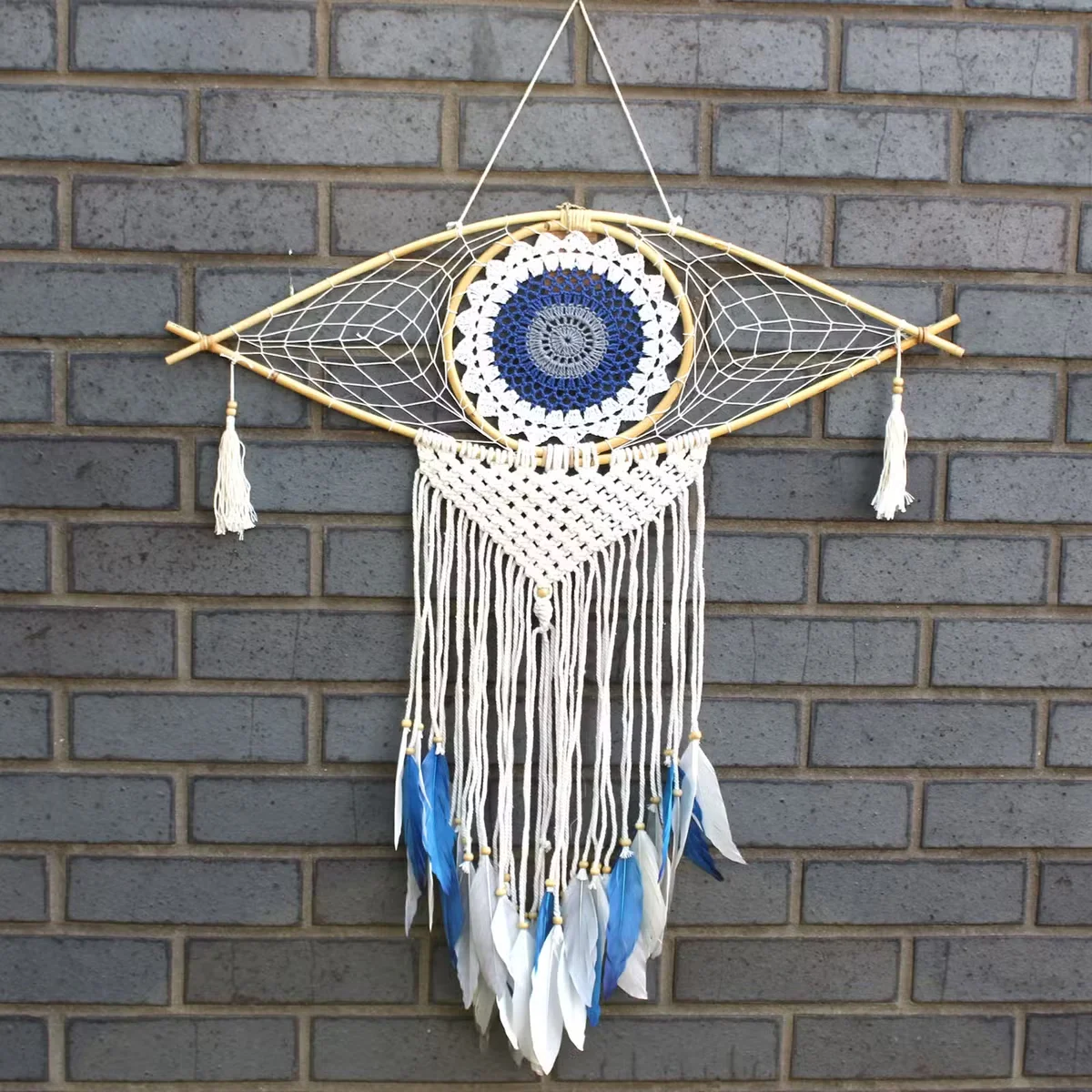 Large macrame white blue grey dream catcher with evil eye design in white, blue, and grey colors hanging on wall