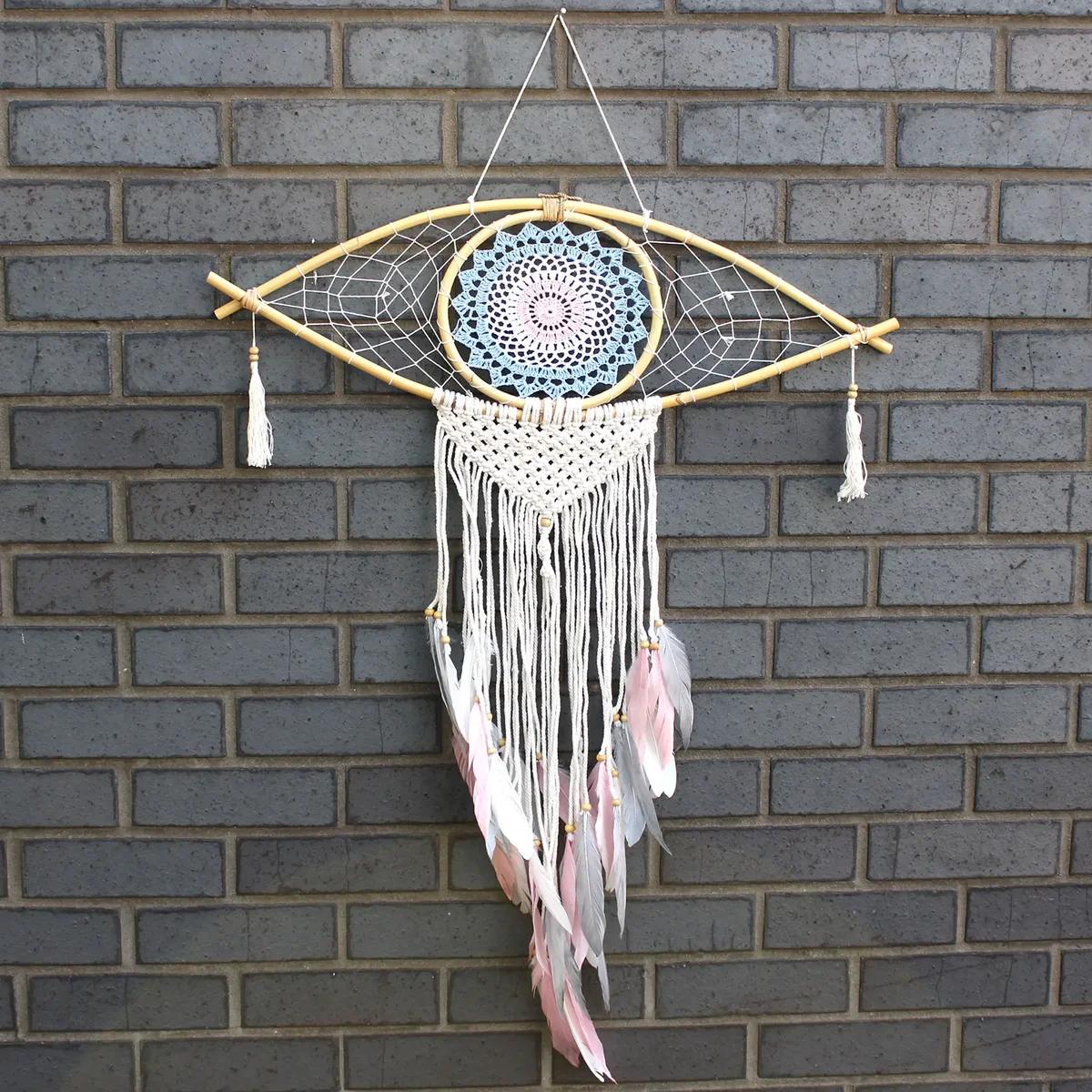 Large macrame dream catcher with blue, white, and pink threads featuring a protective eye design