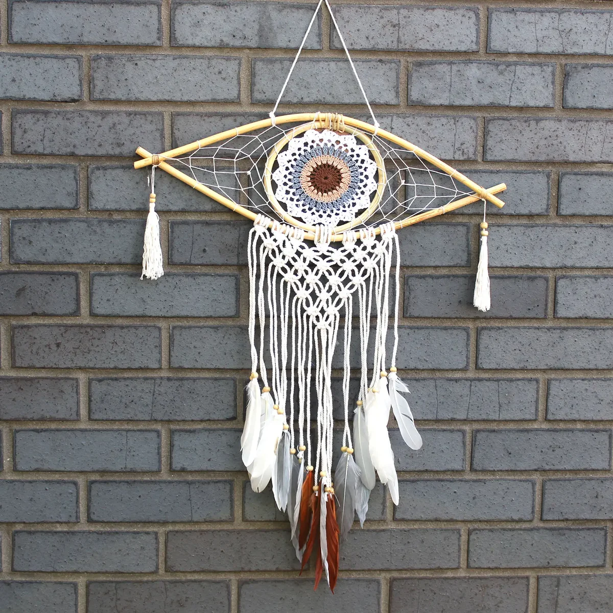 Medium macrame dream catcher in white, grey and brown, with a woven frame and central evil eye decoration.