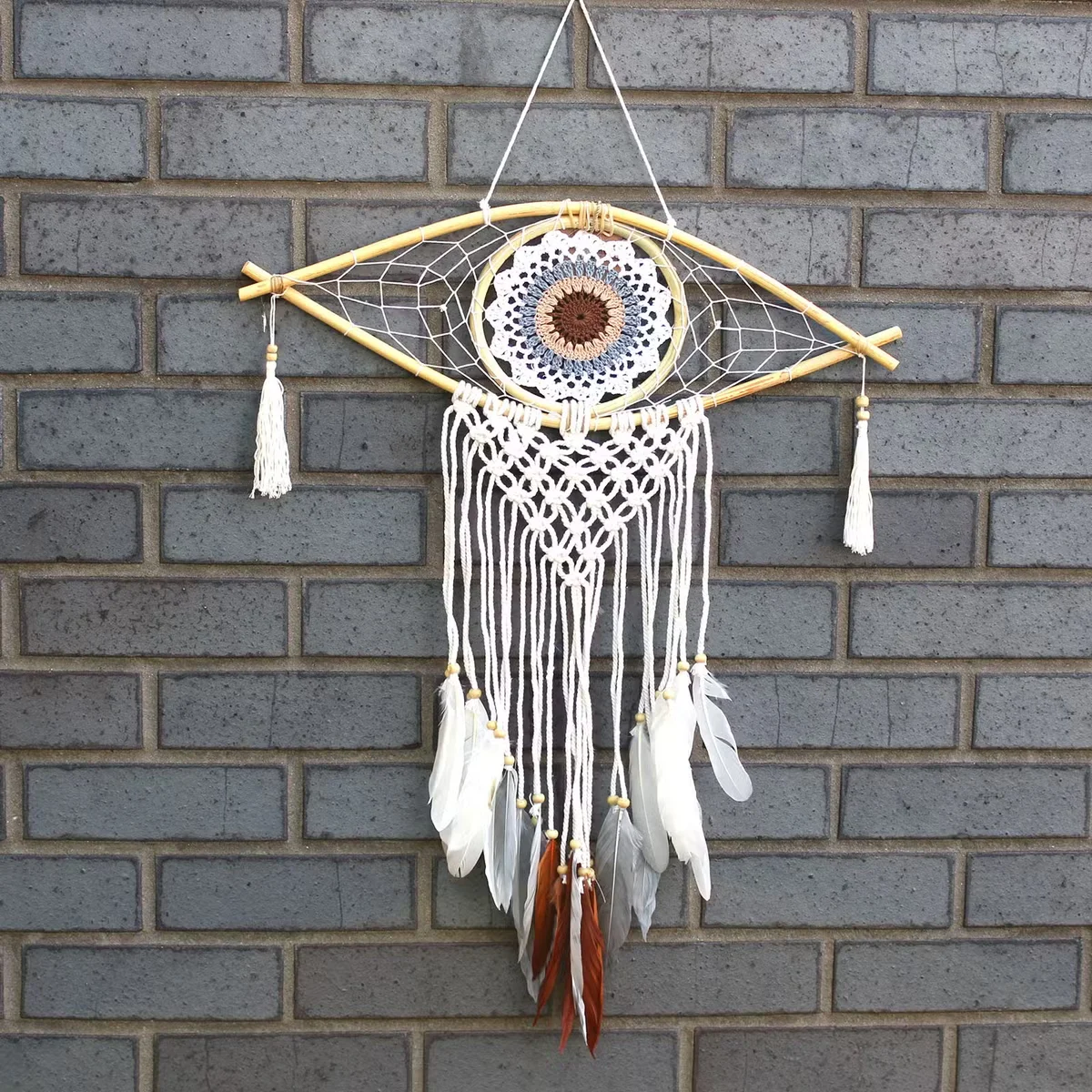 White, grey and brown macrame dream catcher featuring an evil eye charm.