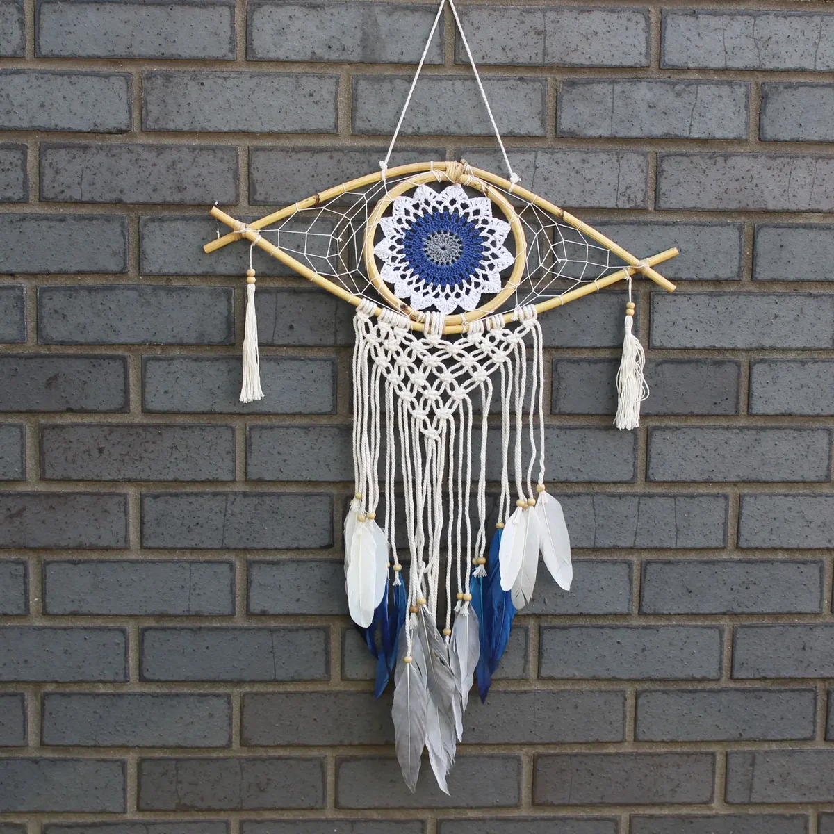 Medium macrame dream catcher featuring white, blue, grey cords and an evil eye charm.