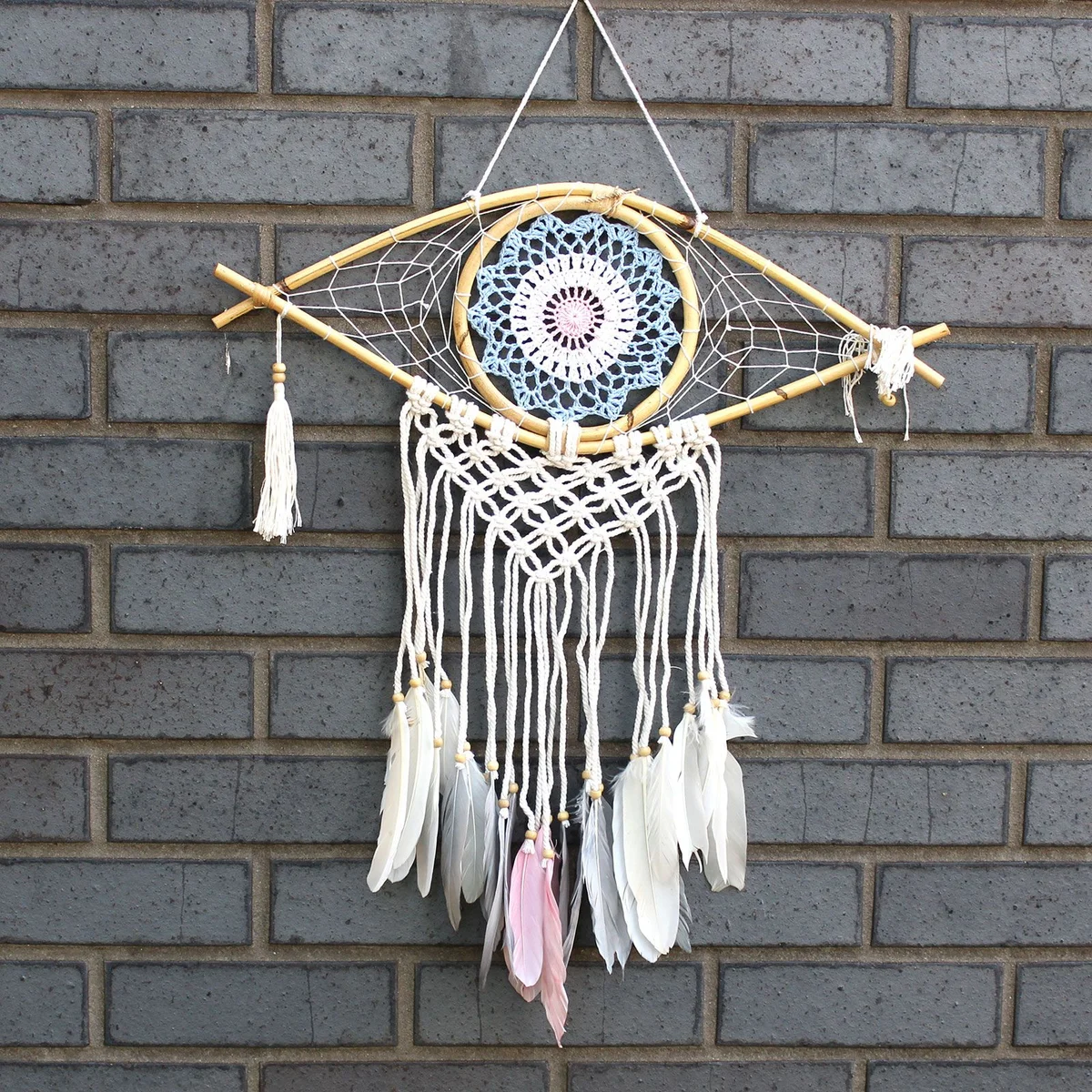 Medium macrame protection dream catcher featuring blue, white, and pink strands with an evil eye charm.
